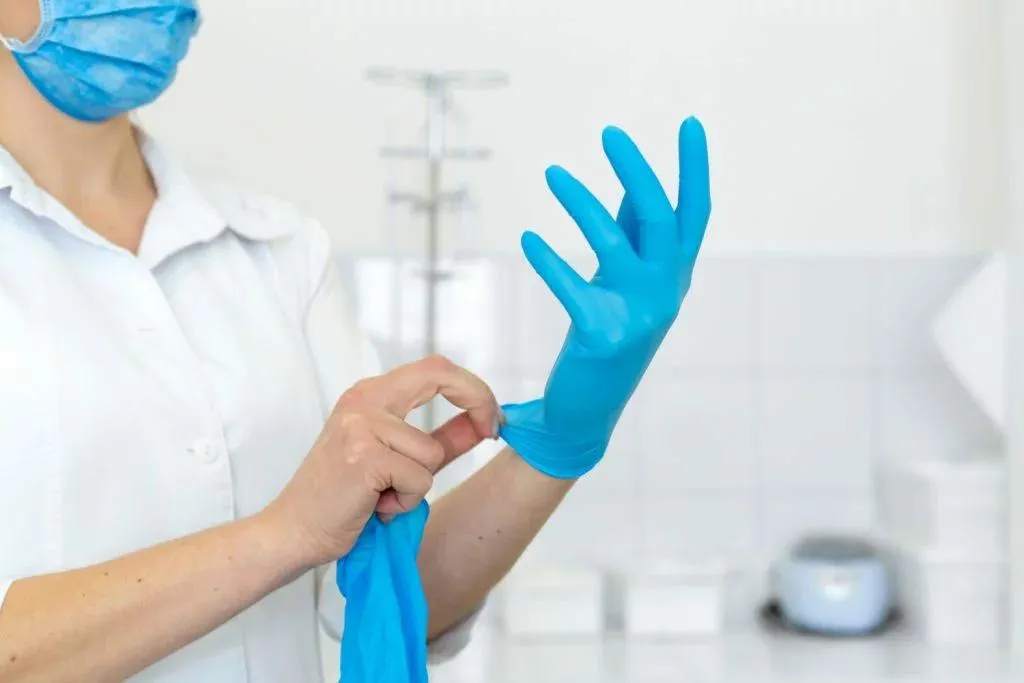 Nhân viên y tế đang đeo găng tay nitrile không bột màu xanh