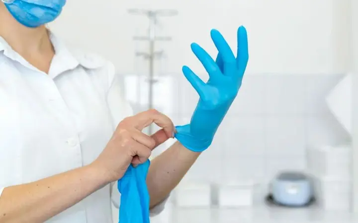 Nhân viên y tế đang đeo găng tay nitrile không bột màu xanh