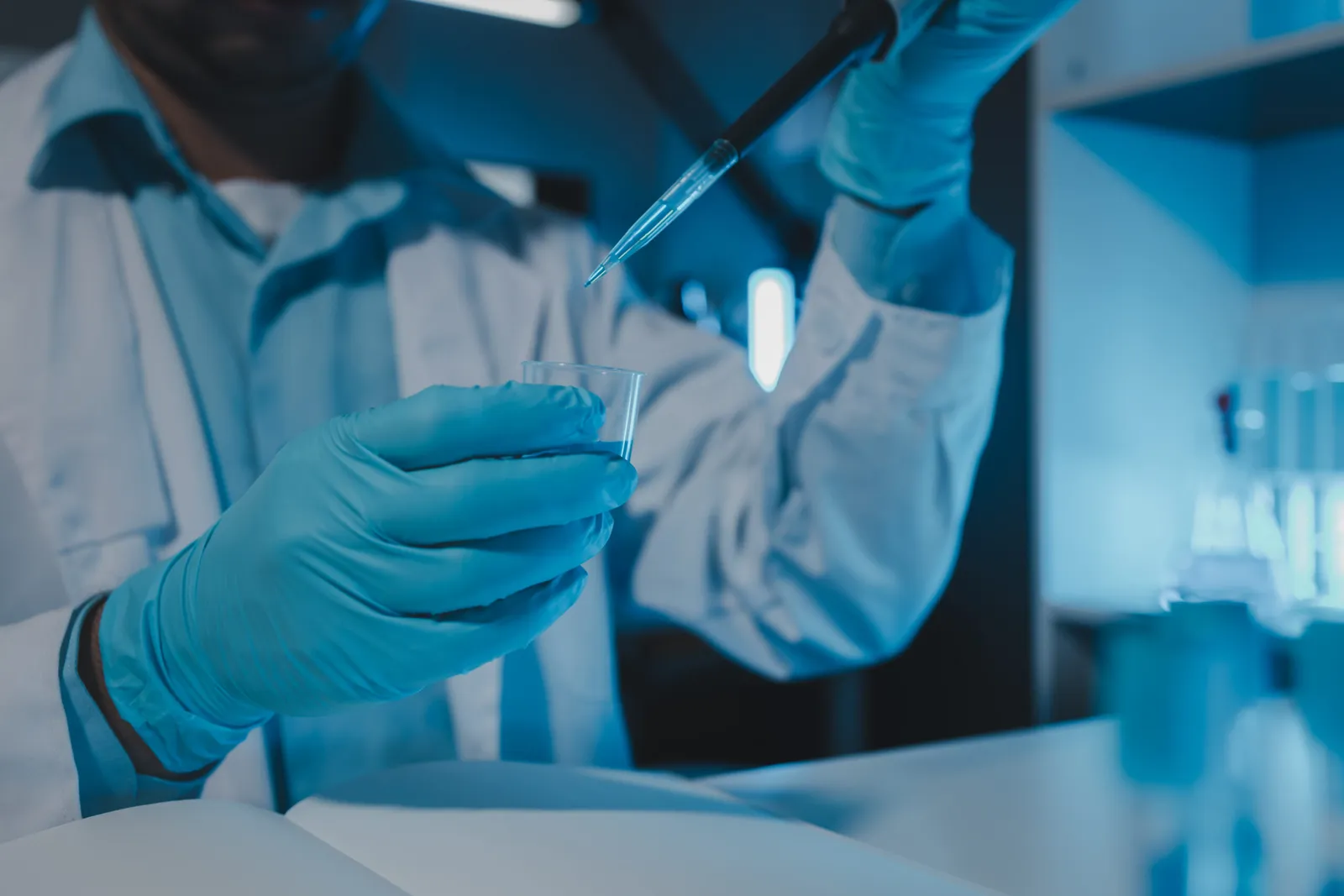 Nhân viên phòng thí nghiệm đeo găng tay nitrile xanh dùng pipet lấy mẫu