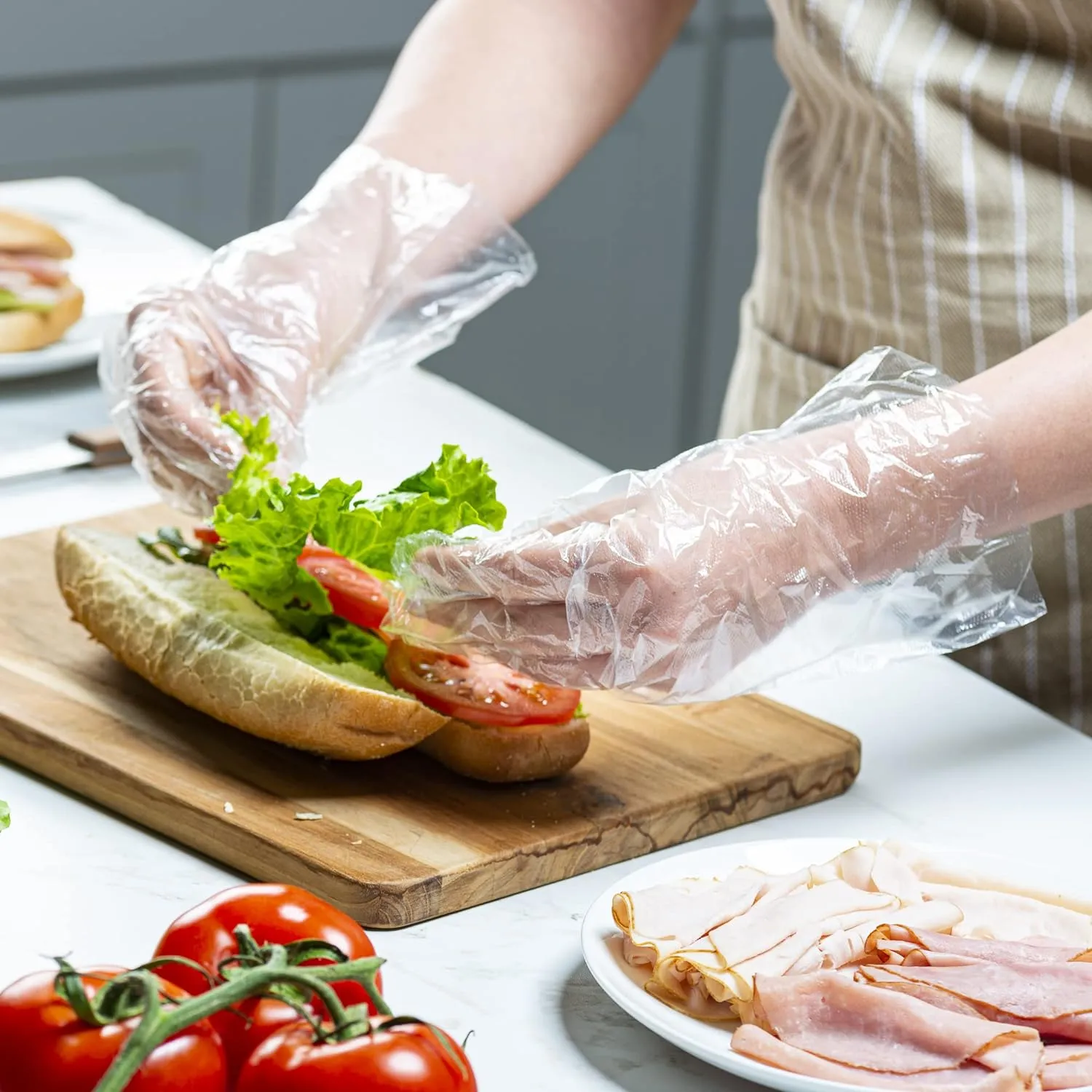 Đôi tay đeo găng tay nilon trong suốt đang làm bánh mì kẹp
