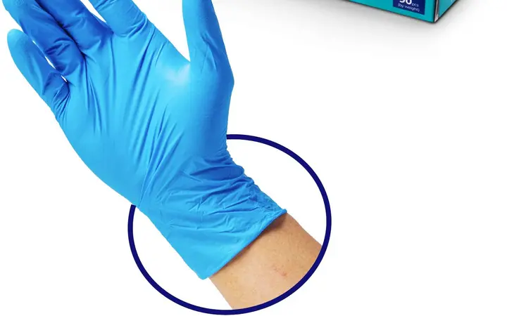Hộp găng tay nitrile không bột màu xanh và một chiếc găng nitrile đeo trên tay